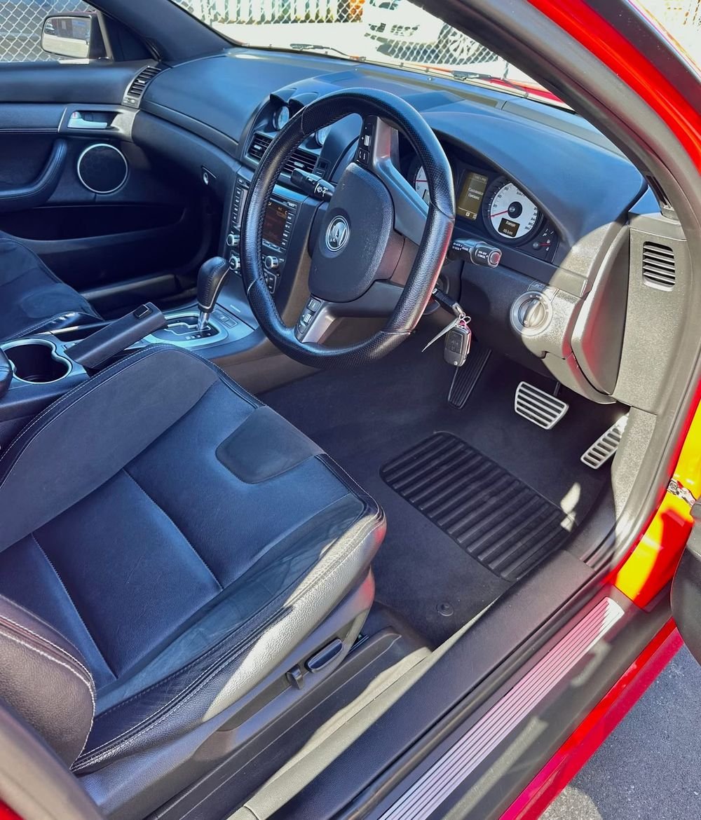 Clean driver seat, carpet and mat inside a red sports sedan